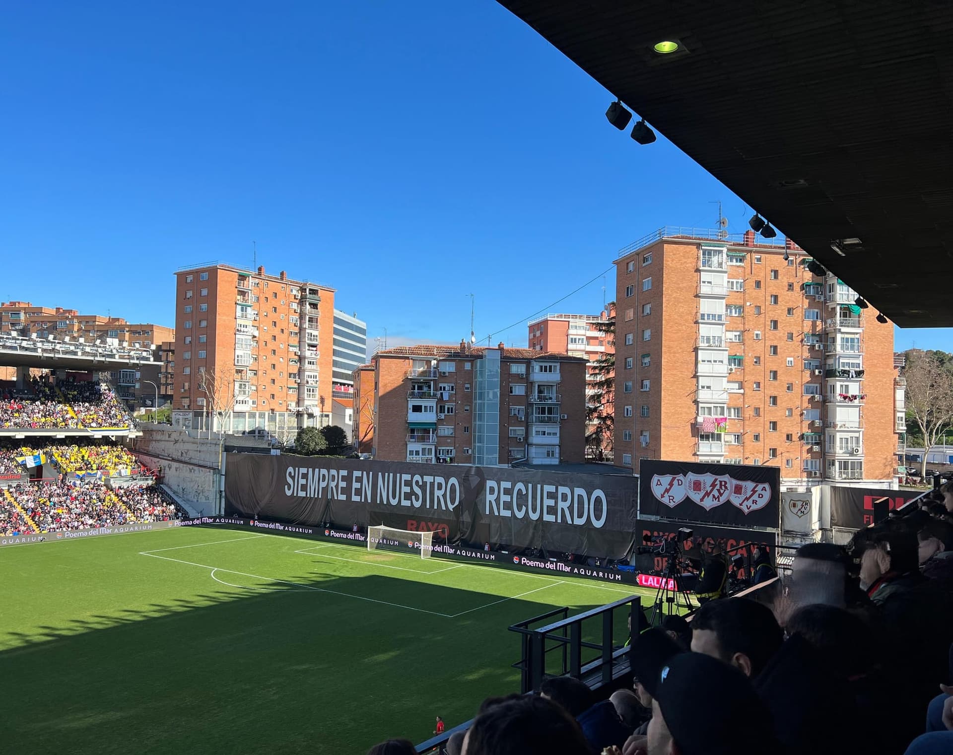 Estadio de Vallecas on a matchday, the apartment blocks of the neighbourhood standing where the fourth stand should be