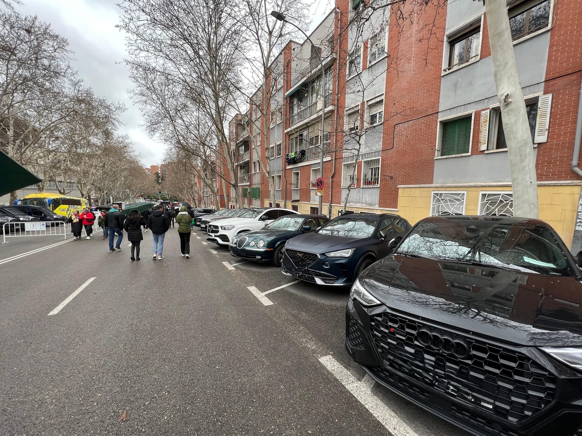 Players' cars parked along the narrow street beside the stadium on a matchday