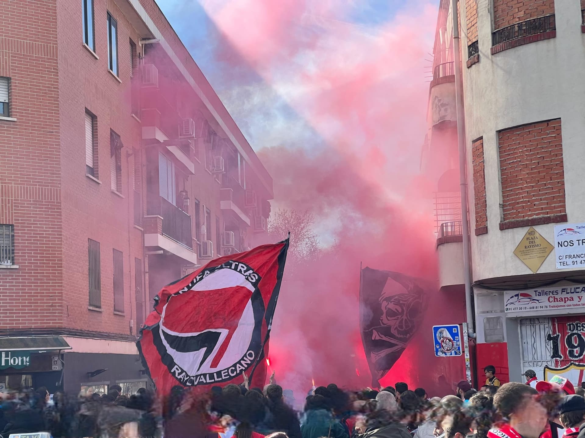 Rayo Vallecano supporters marching to the ground behind red smoke and flags